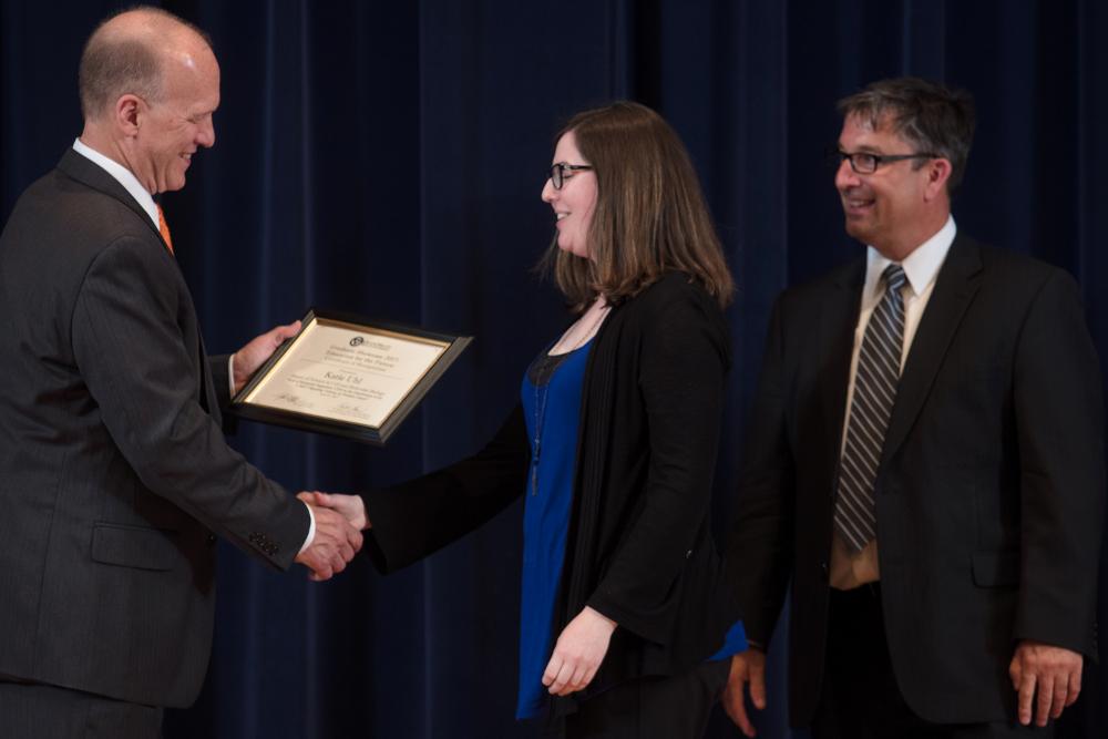 Doctor Potteiger shaking hands with an award recipient in a blue shirt and black sweater